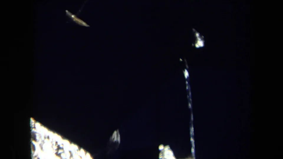 1969 Sacramento 8mm frame showing a dark close-up of reflective machine parts, a thin vertical element, and scattered bright highlights.