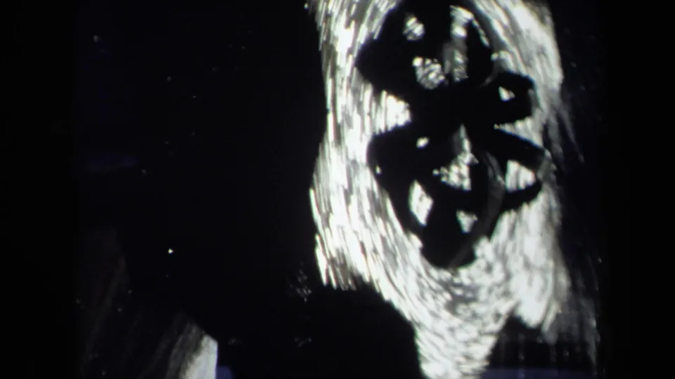 1969 8mm frame showing changing white water forms and streaked highlights against a nearly black background.