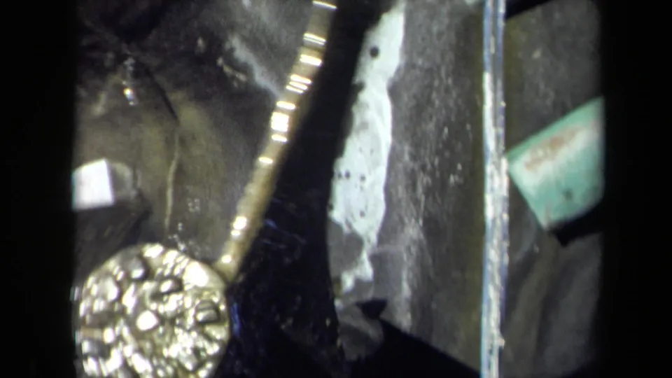 1969 Sacramento 8mm close-up of a gold-toned mill mechanism turning near dark metal parts and running water.