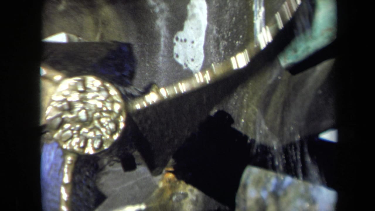Rotating gold-colored gear and dark mill parts seen through a close, grainy frame.
