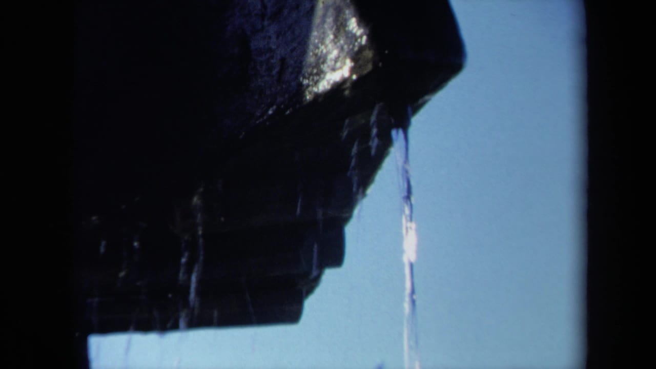 Wet propeller blade fills the upper frame as a thin stream of water falls.