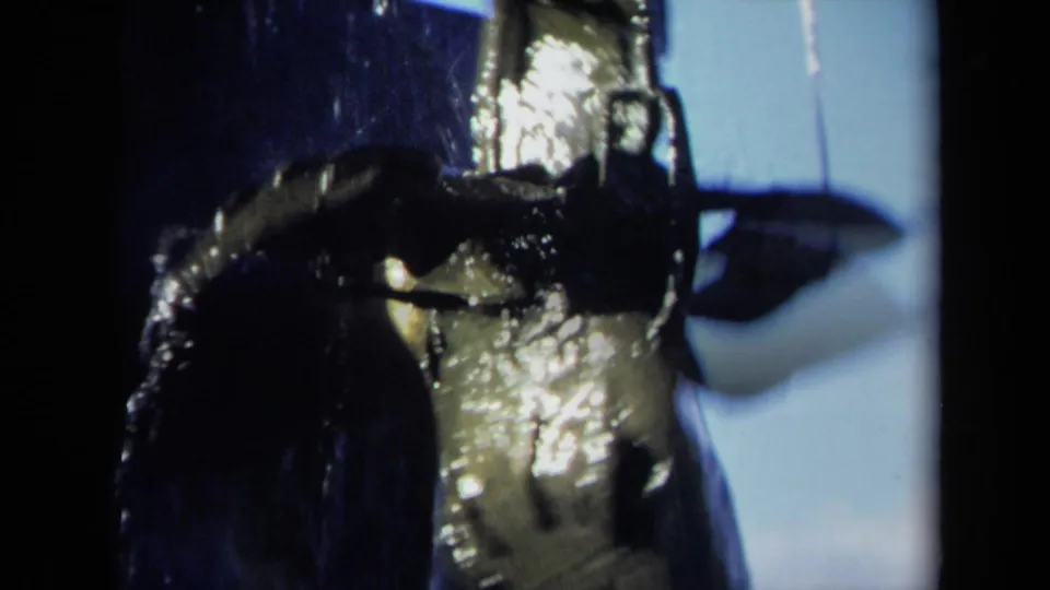 Close 8mm view of wet propeller hardware and blade surfaces catching light, with blue sky visible in the background.