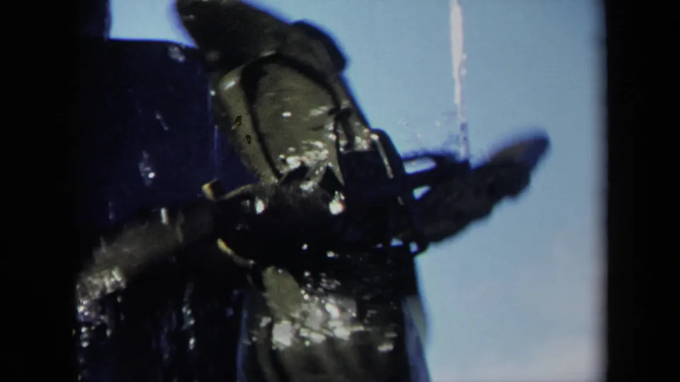 1969 8mm frame from Sacramento showing a close, dark-edged view of a wet boat propeller and shaft with blue sky behind it.