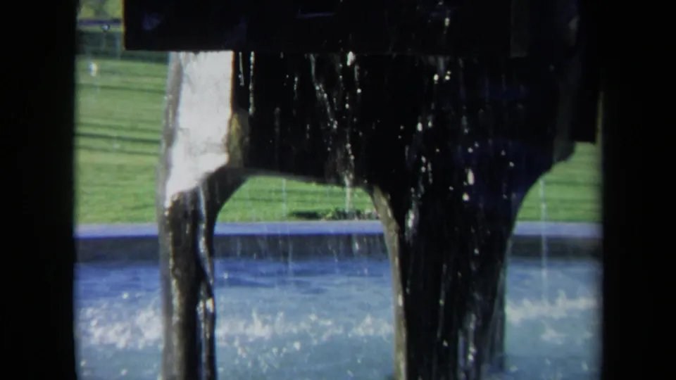 1969 Sacramento frame showing the propeller area splashing water, with a dock edge and green lawn visible beyond the boat structure.