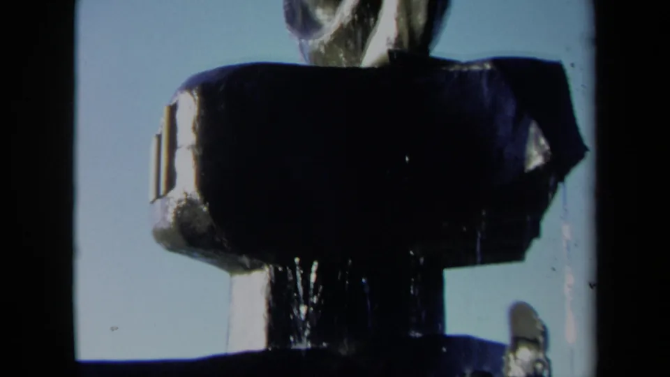 1969 Sacramento 8mm frame showing a shadowed abstract fountain structure with water running down beneath a spiral blade-like sculpture.