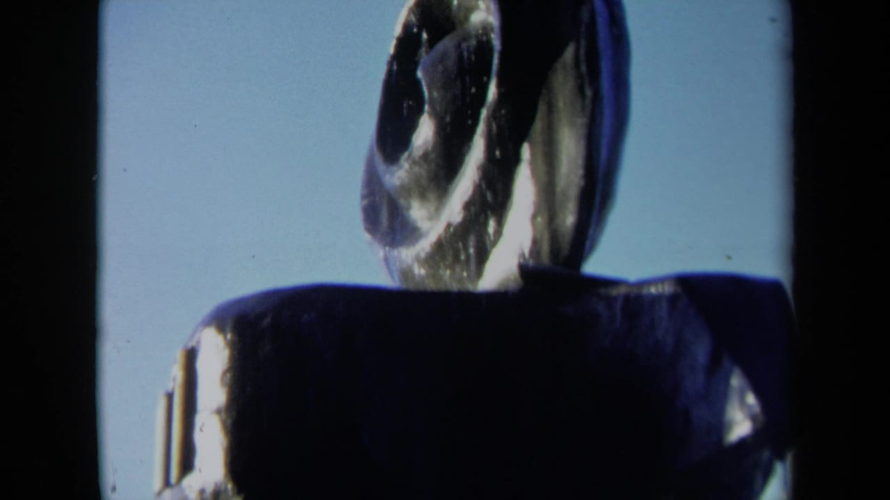 Shadowed fountain top with a spiral blade-like sculpture rising against blue sky.
