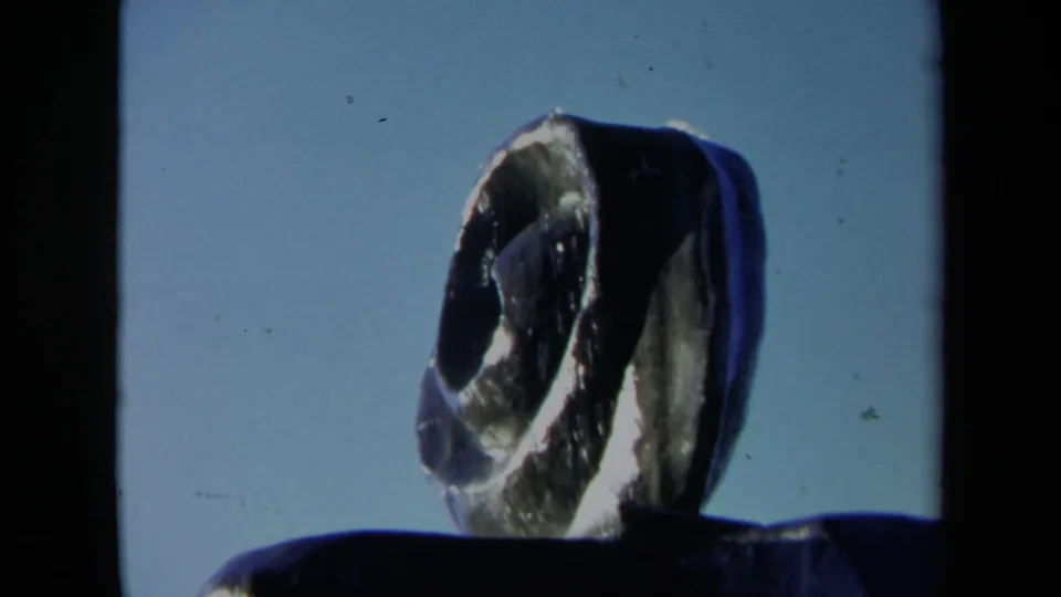 1969 Sacramento home-movie frame centered on the fan-like abstract sculpture with a dark fountain rim below.