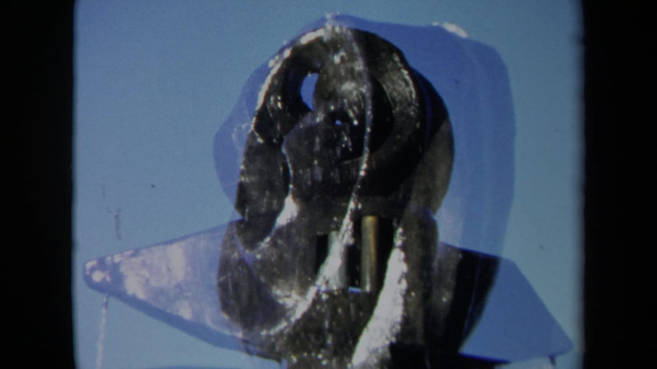 Close 8mm frame of the Sacramento fountain sculpture, with a translucent splash or water sheet visible beside the coiled metal form.