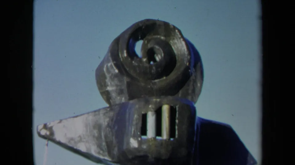 1969 Sacramento 8mm close-up of the coiled fountain sculpture, with basin edge, water movement, and vertical elements below the spiral.