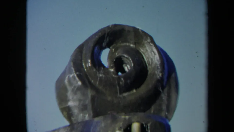 Close 8mm view of the Sacramento spiral fountain form from a low angle, with the dark basin edge and blue sky visible.