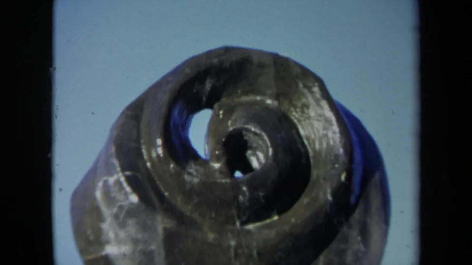 1969 Sacramento 8mm frame showing a close-up of a dark bronze spiral fountain or sculpture with two holes near the center.