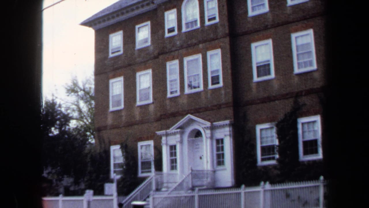1970 Annapolis 8mm frame showing a large brick building with white-trimmed windows, a formal doorway, and a white fence.
