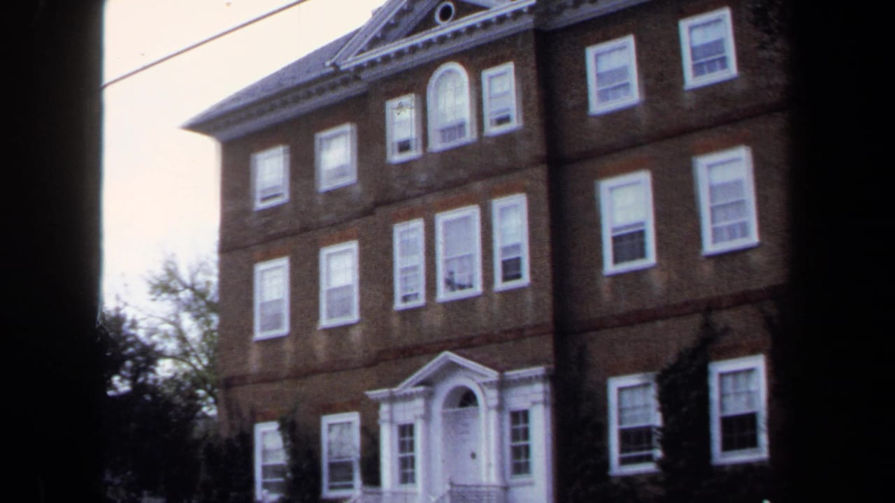 1970 Annapolis frame of a brick institutional-looking facade with white windows, classical trim, trees, and an overhead wire.