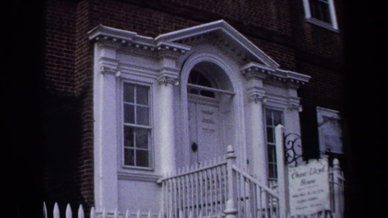 Wide view of the white entrance and sign on a brick historic house.