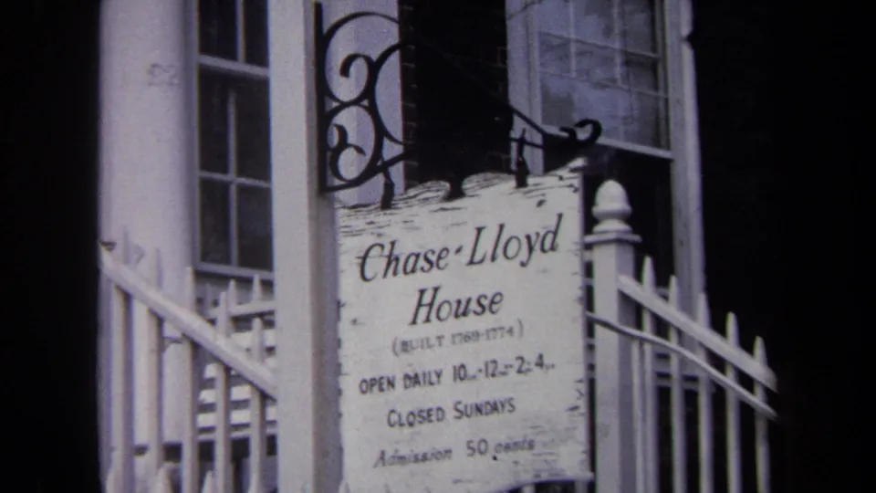 1970 Annapolis frame showing the Chase-Lloyd House visitor sign, white fence, doorway, and wrought hanging bracket.