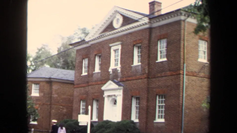 1970 Annapolis frame of the Chase-Lloyd House exterior, showing the front pediment, white entrance, side wing, shrubs, and visitors.