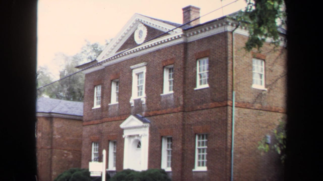 Red brick Hammond-Harwood House facade with white entrance and windows behind a dark vertical film edge.