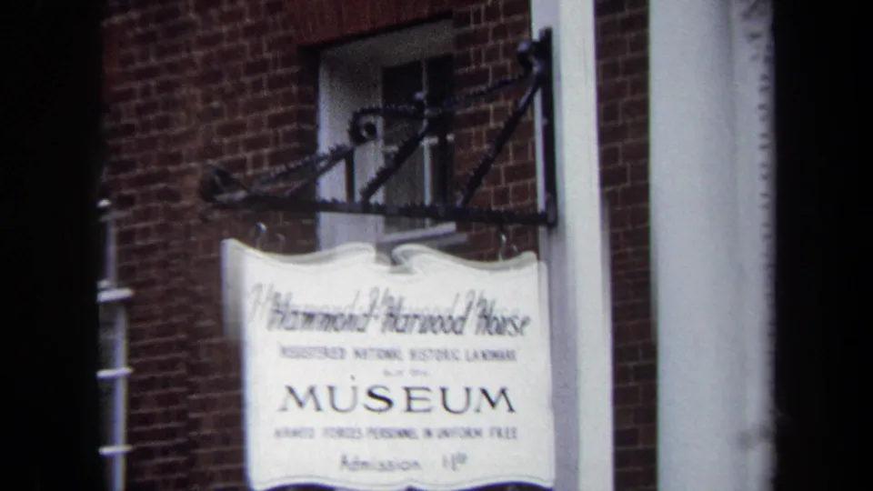 Soft 1970 Annapolis close-up of the Hammond-Harwood House Museum sign, with bracket hardware, brick wall, and white trim visible.