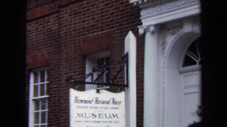 1970 Annapolis home-movie frame showing the Hammond-Harwood House museum sign and white classical entrance on a brick facade.