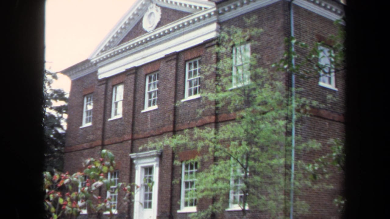 Brick academic building with white-trimmed windows and trees in front.