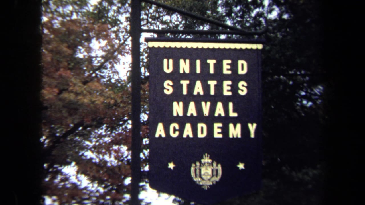United States Naval Academy banner hanging among trees.