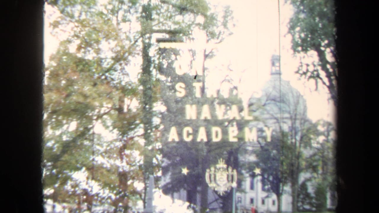 Naval Academy banner partly visible with trees and a domed white building beyond.