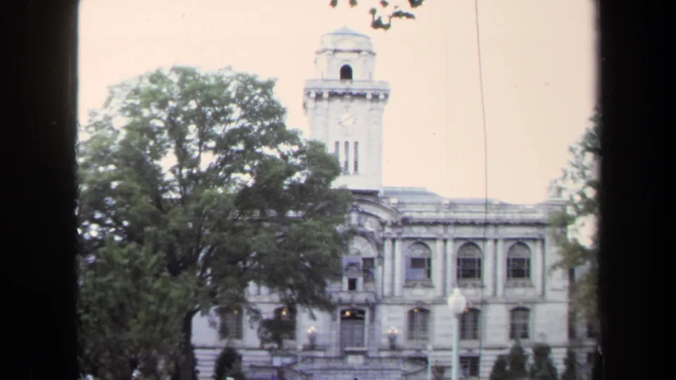 The Annapolis civic building facade and clock tower appear behind leafy trees in faded 1970 8mm color.