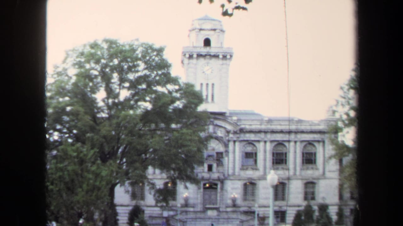Historic building with a clock tower seen through dark window framing.