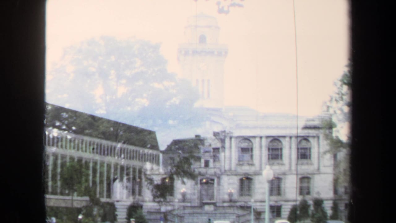 Annapolis 1970 8mm frame with a double-exposed or transitional view of a clock-tower building and a white colonnade.