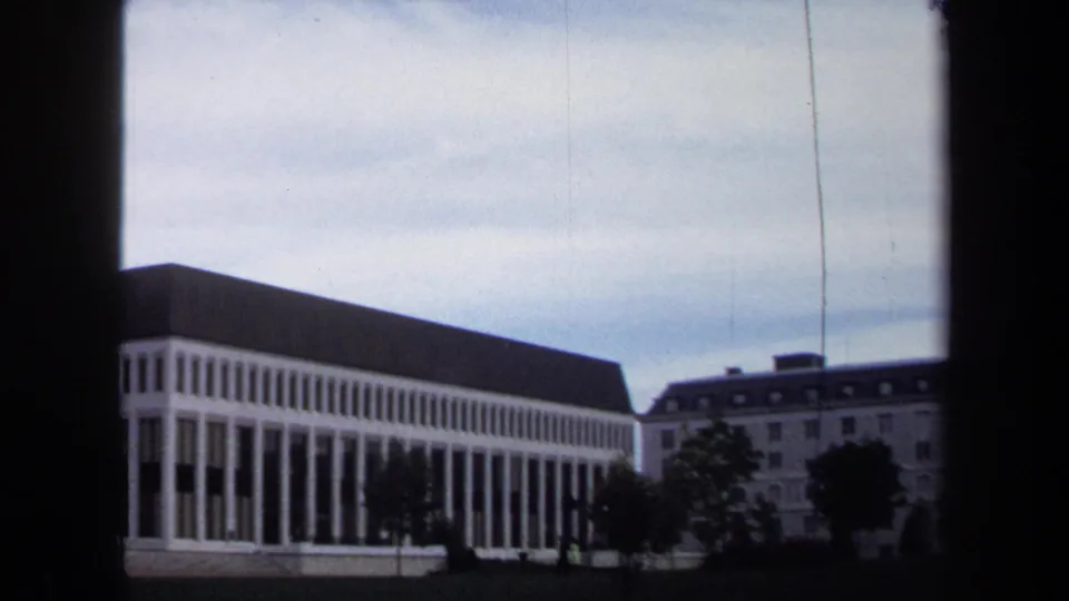 Annapolis 1970 8mm frame showing a modernist white colonnaded building under a gray, overcast sky.