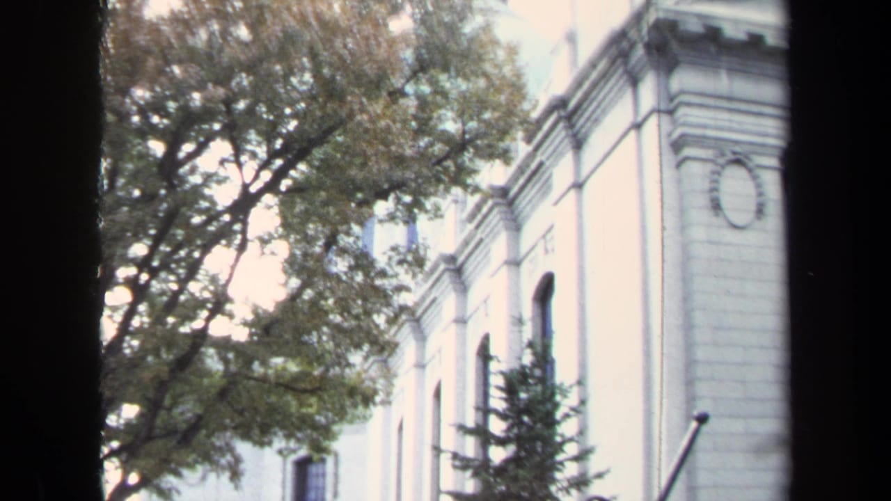 Annapolis exterior detail with arched windows, pale stone walls, trees, and a dark edge from the film or camera framing.