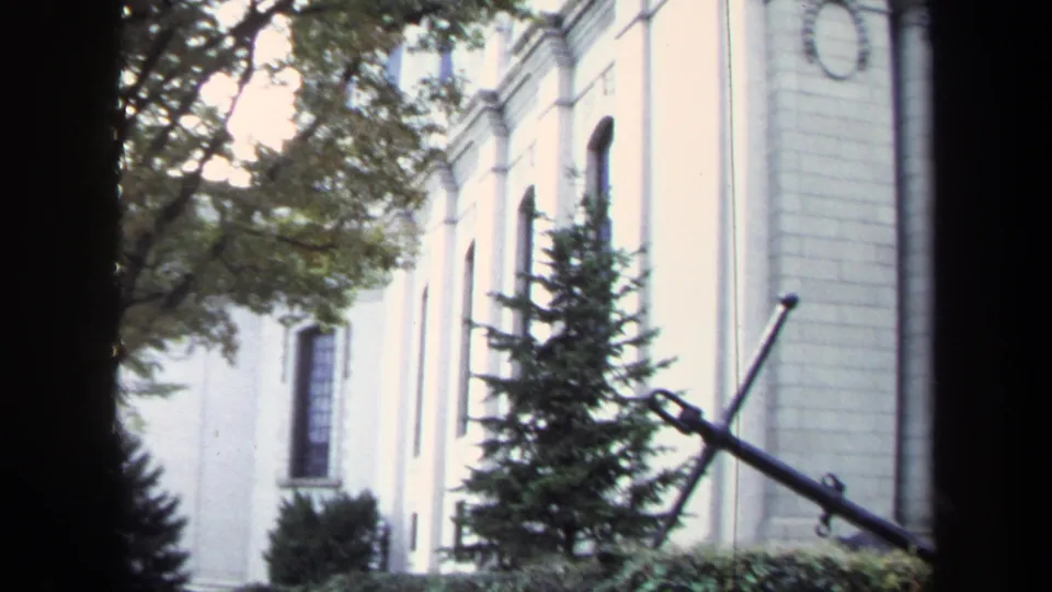 1970 Annapolis frame showing the building side, arched windows, greenery, and a large anchor monument in the foreground.