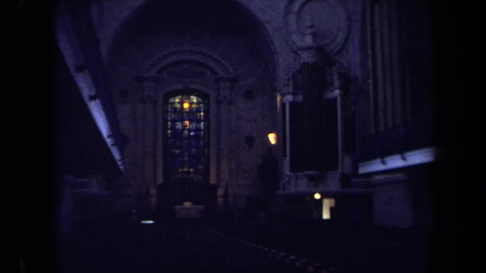 1970s Annapolis 8mm interior view showing a dim church space, stained glass window, lit fixtures, and pipe organ pipes.