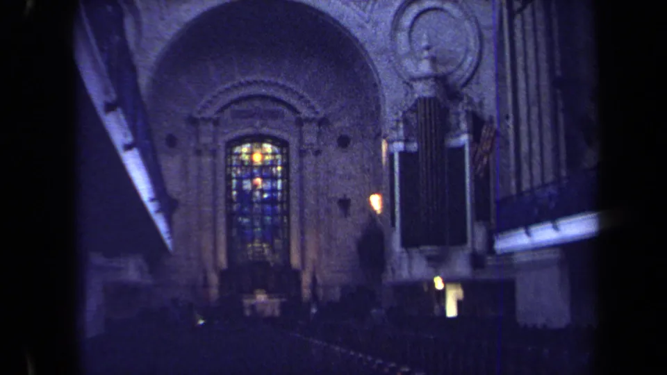 1970 Annapolis 8mm frame showing a church interior with stained glass, carved stone archwork and organ pipes in low blue-toned light.