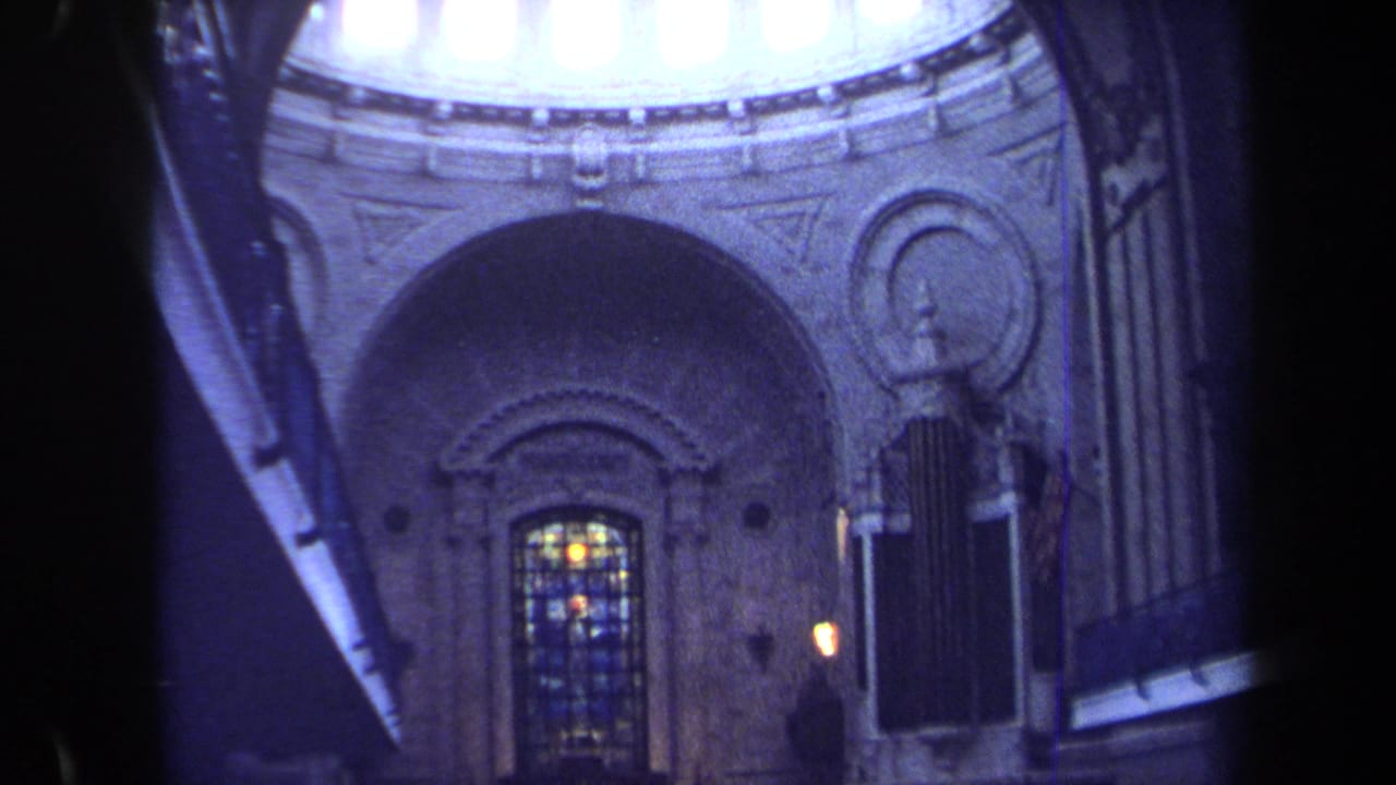 1970 Annapolis 8mm frame looking upward inside a church, with stained glass below arched stonework and a bright dome rim above.