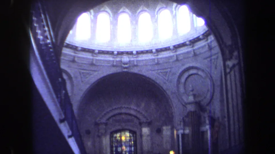 1970 Annapolis 8mm frame of a church dome with bright clerestory windows, stone ornament and stained glass lower in the frame.