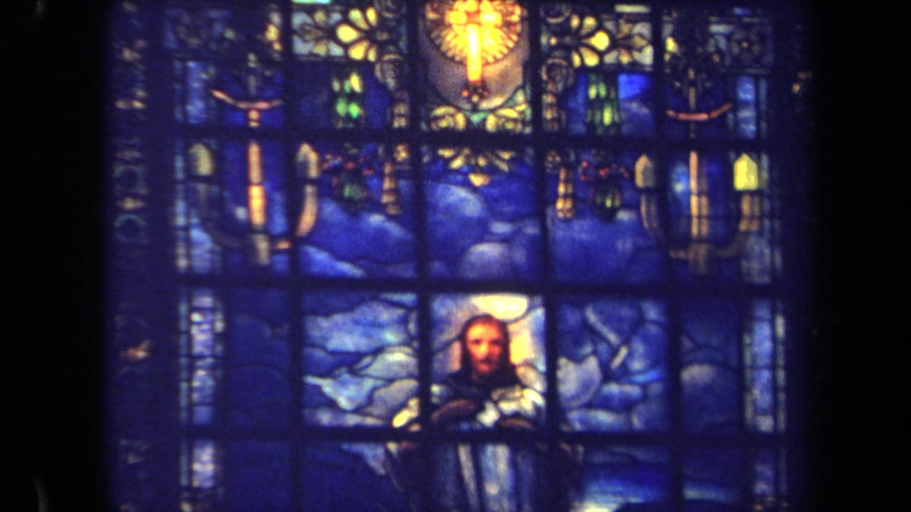 Closer view of a blue stained glass panel with a central religious figure.