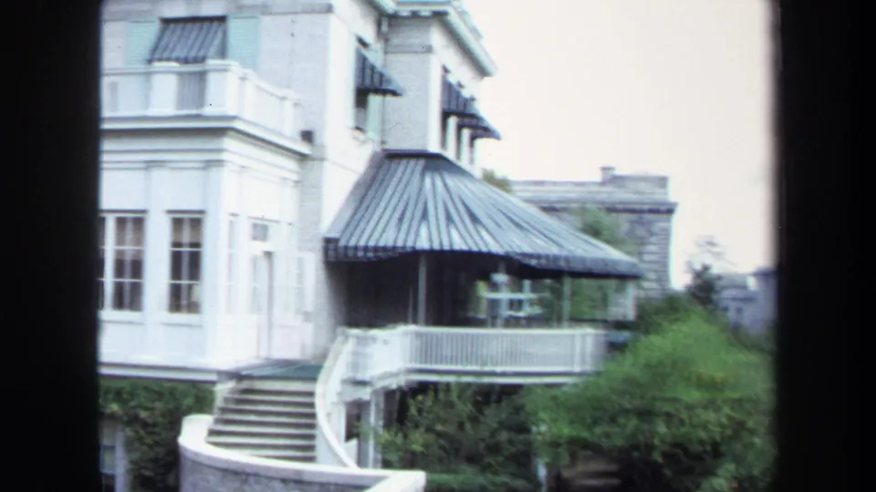 1970 Annapolis vacation footage showing a white historic-looking building exterior with striped awnings, stairs, railing, and shrubs.