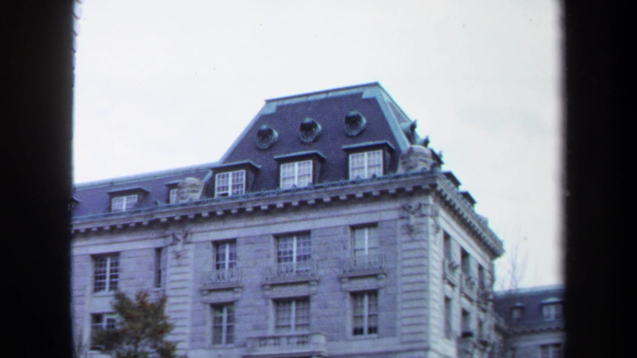 1970 Annapolis 8mm frame showing an ornate stone building roofline, mansard roof, dormers, and window-edge framing.
