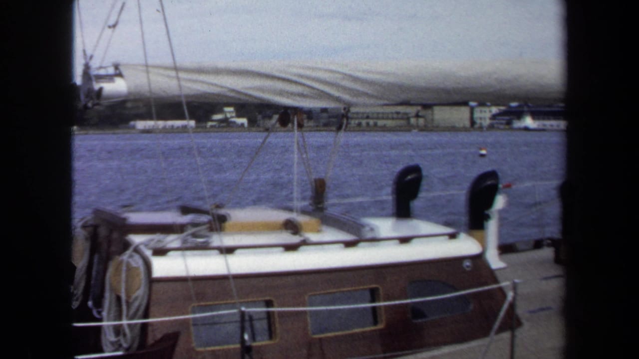 1970 Annapolis 8mm frame showing a sailboat cabin, deck ropes, railings, and blue water beyond.