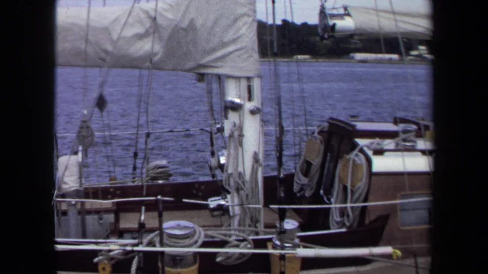 1970 Annapolis 8mm still showing sailboat rigging, cabin roof, coiled lines, railings, and harbor water.