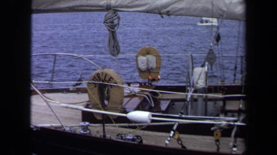1970 Annapolis sailboat deck view showing the JUBILEE life ring, railings, ropes, rigging, and water under a canvas edge.