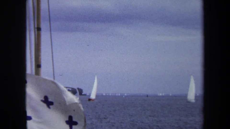 1970 Annapolis boating view with a white flag bearing blue crosses in the foreground and small sailboats on the horizon.