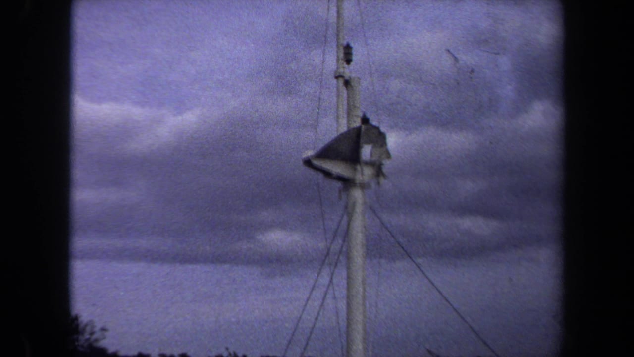 White tower and torn flag centered against a purple-gray cloudy sky.