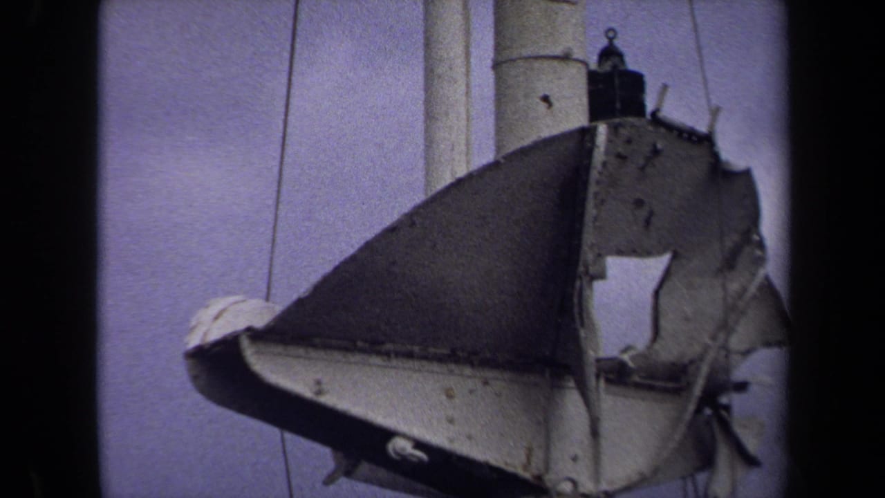 Closer view of the torn hanging object beside a pale pole and sky.
