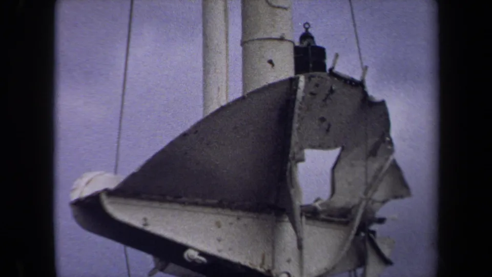 1970 Annapolis 8mm footage frames the weathered hanging object from below, emphasizing its hole, pole, and surrounding lines.