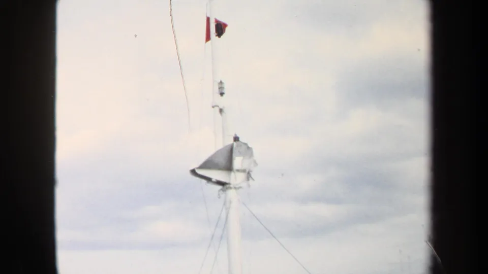 1970 Annapolis 8mm frame showing a small flag above the white mast, with torn material and rigging visible below.