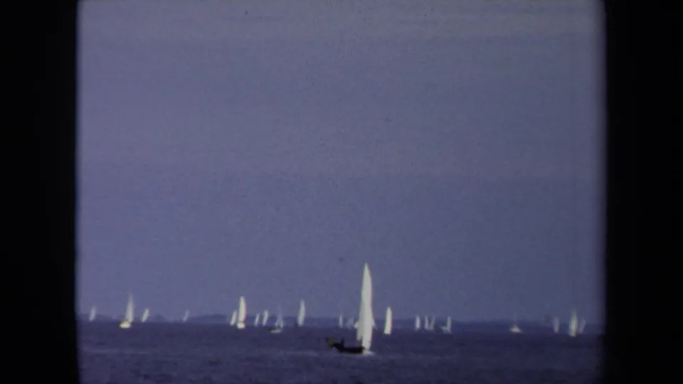 1970 Annapolis sailing view with small white sails scattered across calm water beneath a blue-gray horizon.