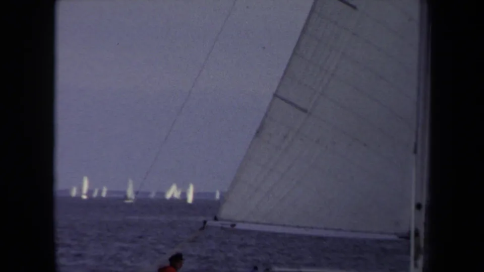 A 1970 Annapolis sailing view includes foreground sailcloth, distant boats, and a partial person at the bottom edge.