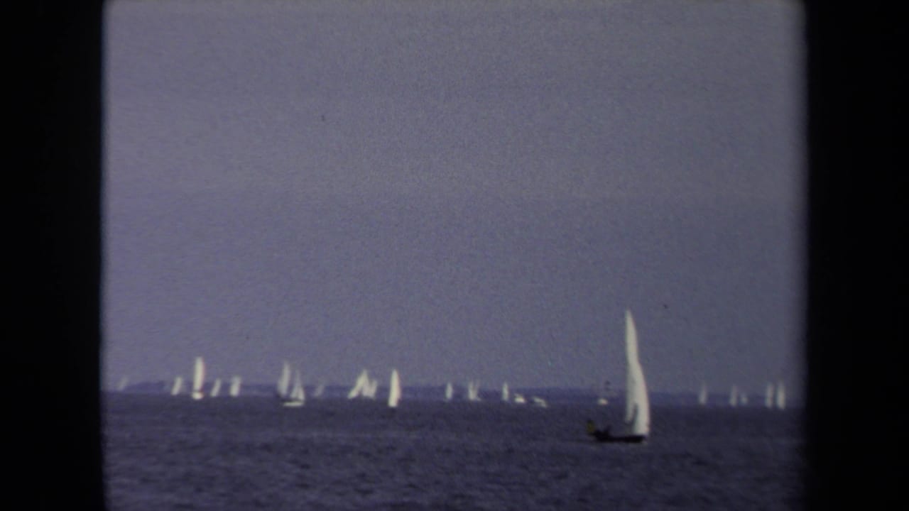 1970 Annapolis 8mm frame showing many distant sailboats on open water, with one larger white sail nearer the foreground.